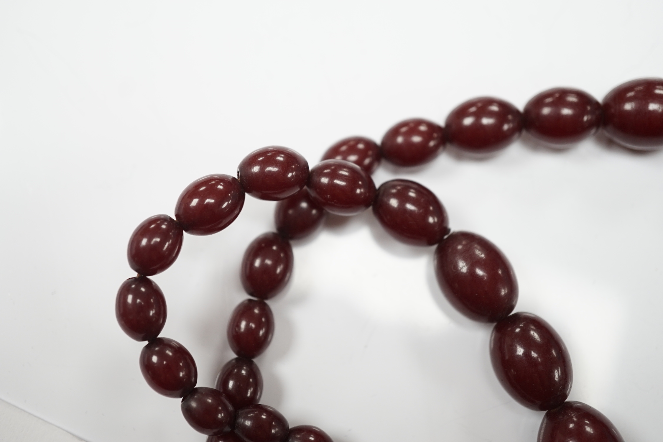 A single strand graduated simulated oval cherry amber bead necklace, 58cm, gross weight 80 grams.